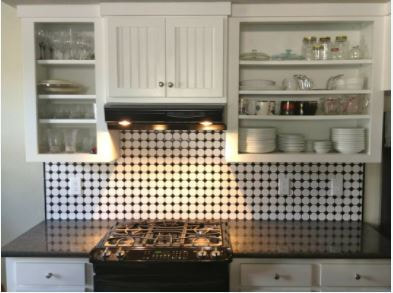 White kitchen cabinets with black spotted white backsplash 